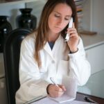 lady doctor using phone while taking notes