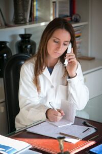 lady doctor using phone while taking notes